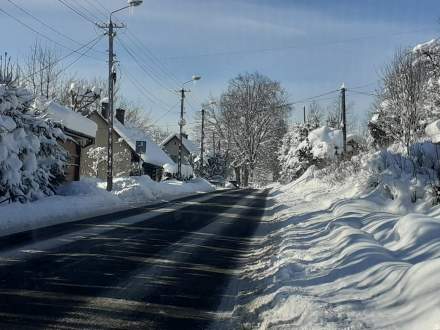 Droga powiatowa w Istebnej Dziedzinie; zaśnieżony chodnik, domy; błękitne niebo