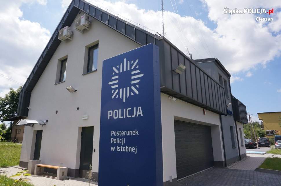 Biało-szary budynek z niebieskim pylonem z napisem: POLICJA Posterunku Policji w Istebnej, f. slaska.policja.pl